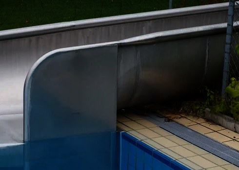 Close-up of a stainless steel run-out with impact protection, adjacent to the pool.