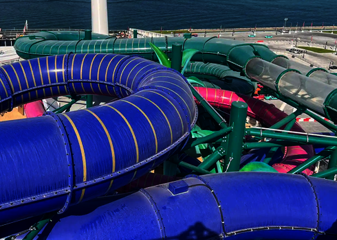 Grüne 2-in-1 Racer Wasserrutsche und Röhrenrutschen in Blau und Pink auf einem Kreuzfahrtschiff.