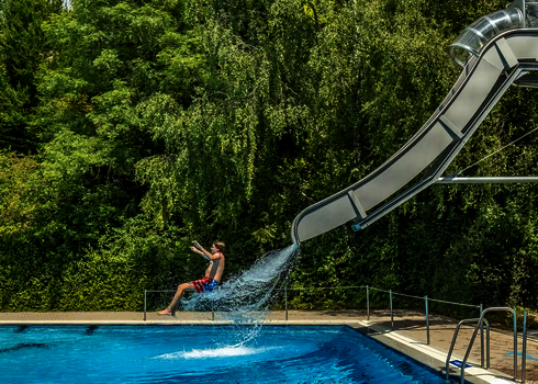 Eine Person in Badebekleidung rutscht die Fallstart Wasserrutsche herunter.