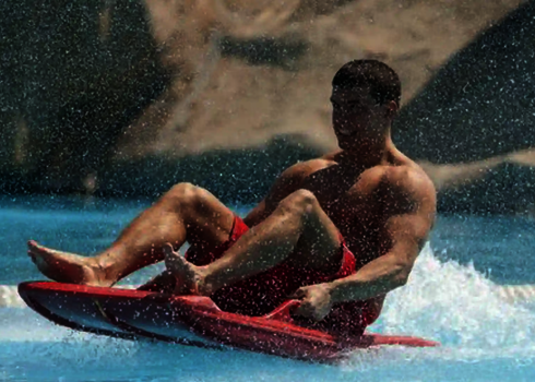 Mann hält sich an den Riemen an einem Boot fest, das Wasser spritzt.