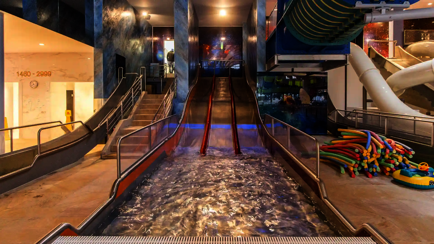 Dreibahnige Edelstahlrutsche Trio-Slide in einer Badehalle, Blick vom Landebecken aus.