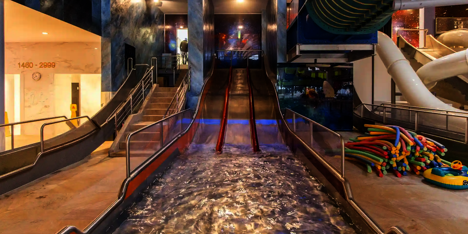 Dreibahnige Edelstahlrutsche Trio-Slide in einer Badehalle, Blick vom Landebecken aus.