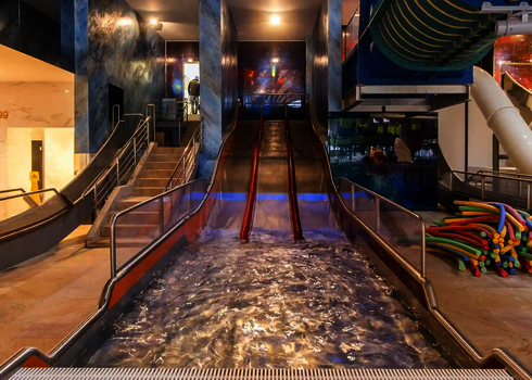 Dreibahnige Edelstahlrutsche Trio-Slide in einer Badehalle, Blick vom Landebecken aus.