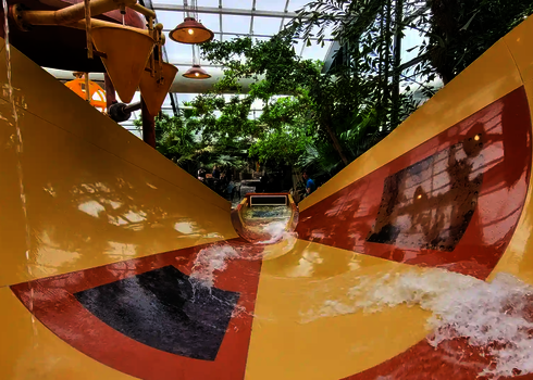 Blick von einer großen gelben Wasserrutsche in tropischer Umgebung.