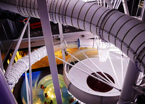 Innenansicht eines Hallenbads mit weißen Wasserrutsche und einer Body Bowl.