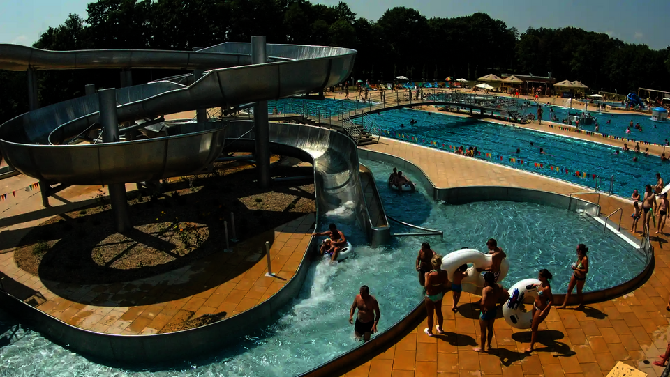 Wasserrutsche aus Edelstahl mit Lazy River und Besuchern auf Rutschreifen.