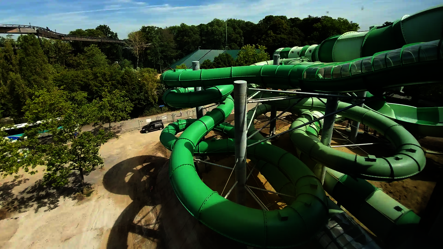 Der grüne Rutschenturm der Raft Racer Wasserrutsche mit mehreren Spiralröhren im Außenbereich.