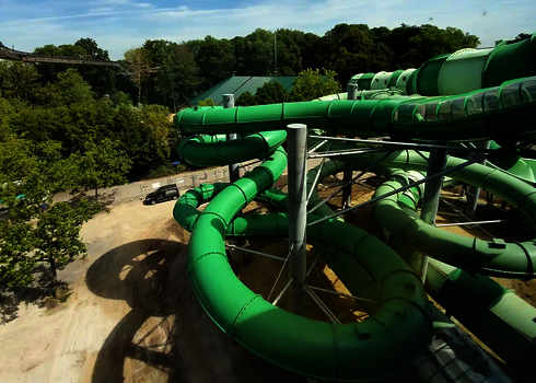 Der grüne Rutschenturm der Raft Racer Wasserrutsche mit mehreren Spiralröhren im Außenbereich.