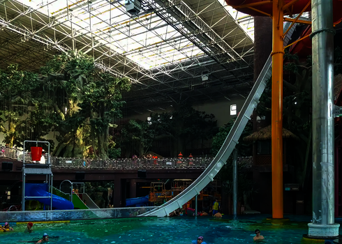 Freifallrutsche im Innenbereich eines Hallenbades mit fast senkrechtem Verlauf über ein Wasserbecken.