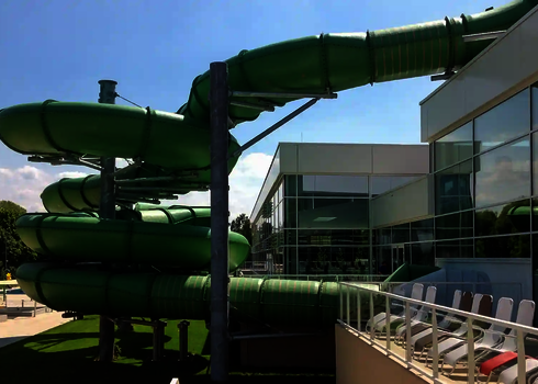 Seitenansicht der grünen Family Twister Außenrutsche an einem Freizeitbad.