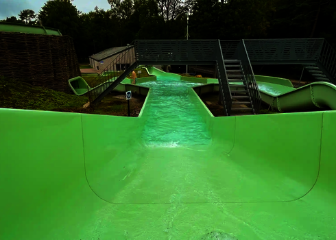 Sicht von oben eines grünen Wildwasserflusses auf ein Becken mit mehreren Abgängen.