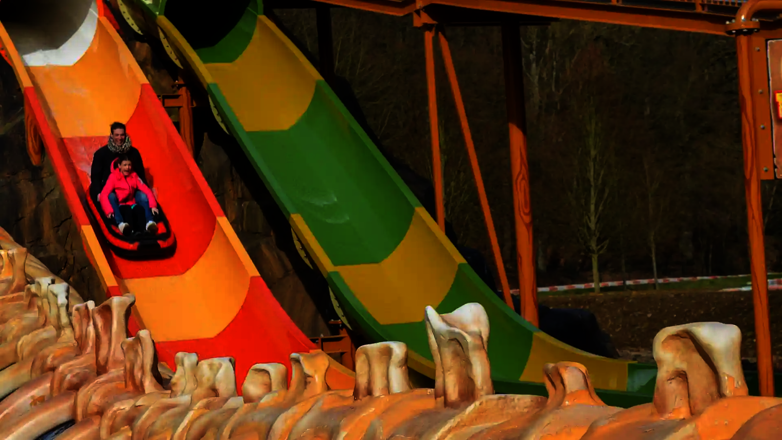 Bunte Harakiri-Wasserrutsche, zwei Personen rutschen auf einem Boot herunter.