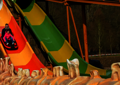 Bunte Harakiri-Wasserrutsche, zwei Personen rutschen auf einem Boot herunter.