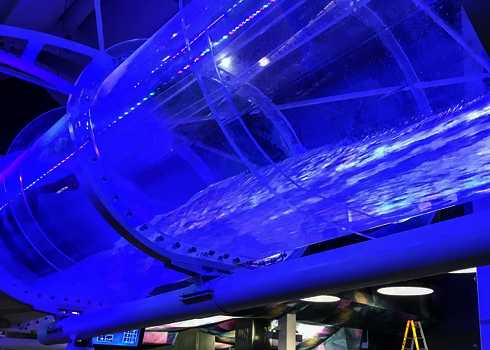 Acrylröhre mit blauer LED-Beleuchtung zeigt Wasserströmung in einer Indoor-Wasserrutsche.