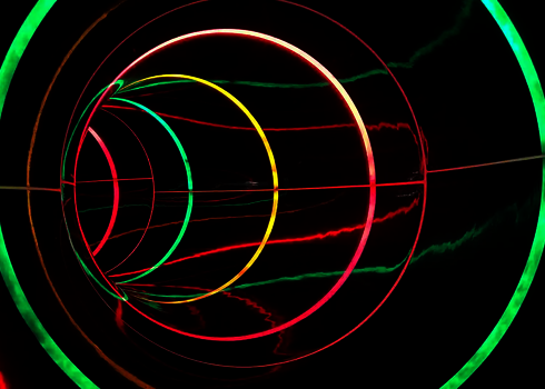 Eine dunkle Wasserrutsche mit grünen, gelben und pinken Lichtkreisen.