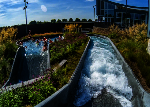 Belebter Sammelbereich im Wildwasserfluss mit Pflanzeninsel und angrenzendem Becken.