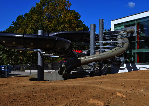 Schwarze und graue Family Twister Wasserrutsche mit Stahlstützen am Hallenbad.