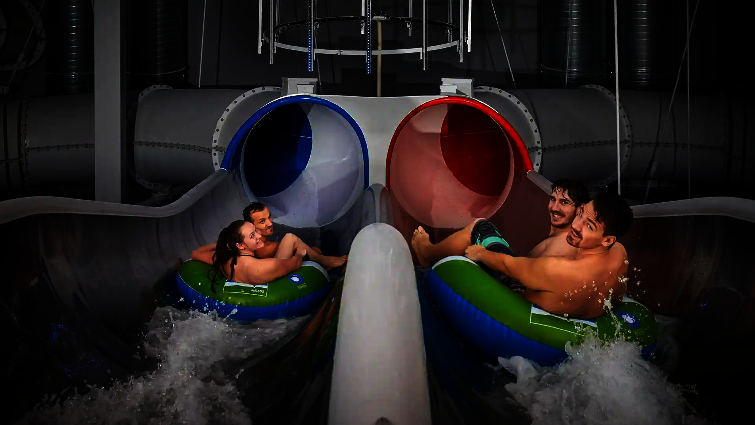 Zwei Teams rutschen parallel in die blau-rote Raft Racer Reifenrutsche mit Wassereinstieg.