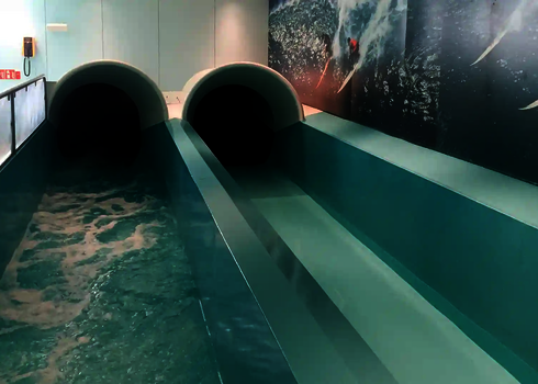 Two dark tunnel slides end in parallel lanes of a turquoise pool.