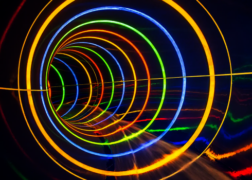 Innenansicht einer dunkeln Wasserrutsche mit bunt-gestreiften Tageslichteffekten.