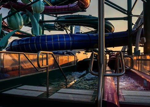 Zwei Rutschen mit glatter blauer und violetter Oberfläche enden nebeneinander im Becken.