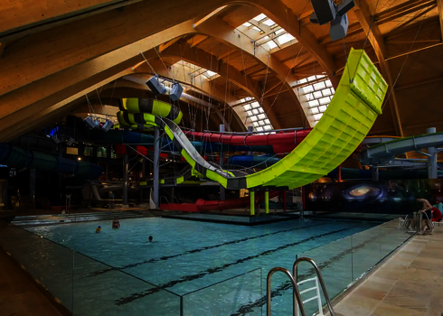 Die gelb-graue Boomerang-Rutsche verläuft durch ein Erlebnisbad mit Glasdach.