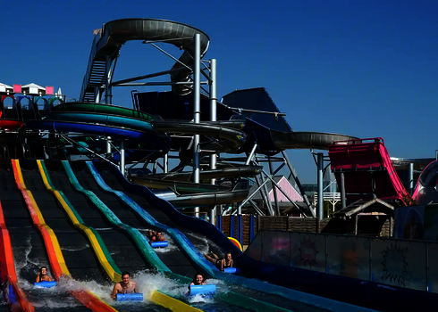 Mehrere Personen rutschen nebeneinander auf Matten die Wasserrutsche Matracer hinunter.
