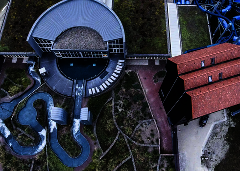 Drohnenaufnahme zeigt den geschwungenen Verlauf des Wildwasserflusses um das Gebäude.