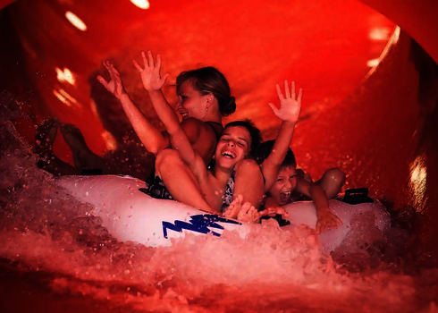 Familie rutscht gemeinsam auf einem weißen Reifen durch die Family Twister Wasserrutsche.