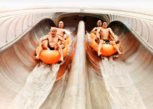 Zwei Teams rutschen parallel in orangefarbenen Reifen auf der Raft Racer Wasserrutsche hinab.