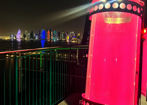 Pinke U-Drop-Kapsel auf einer Plattform mit Blick auf eine nächtlich beleuchtete Skyline.