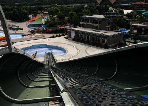 View from above into a green raft conveyor with conveyor belt in an empty water park.