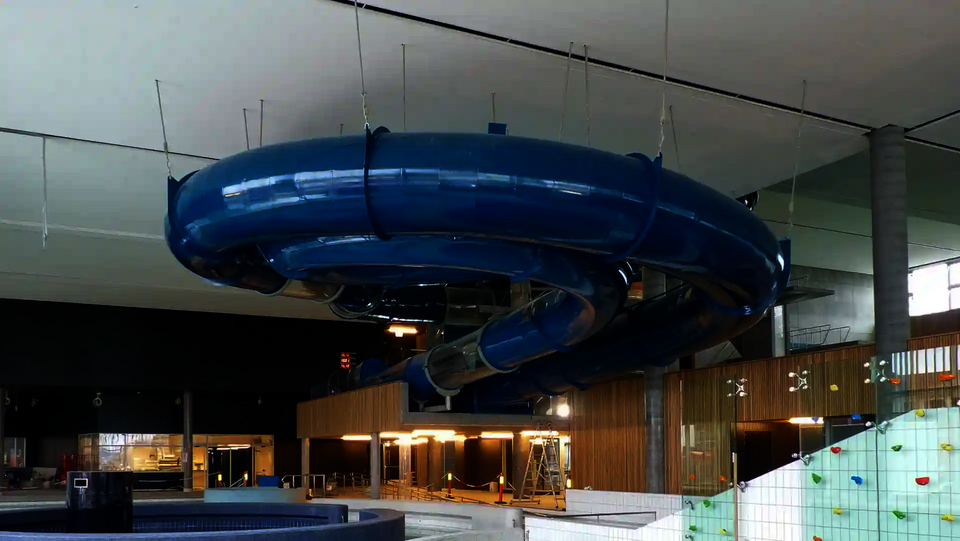 Eine blaue RR1200 Wasserrutsche in einem Hallenbad.