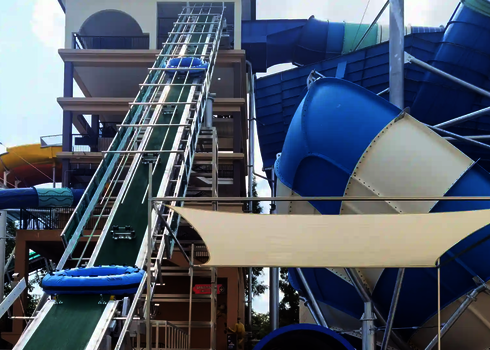 Close-up of a blue four-person slide raft on a green conveyor belt.