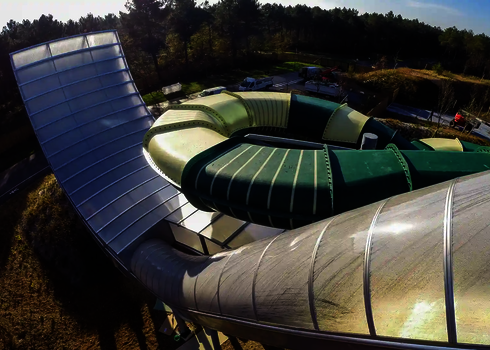 Blick von oben auf eine überdachte Boomerang-Rutsche und einen gelb-grünen Family Twister.