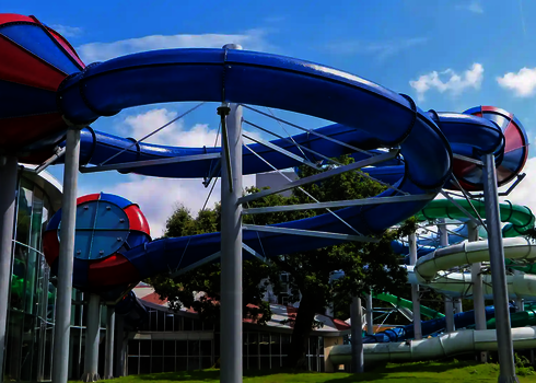 Blau-Rote Crazy Cone Wasserrutsche mit geschwungenem Verlauf an einem modernen Gebäude.