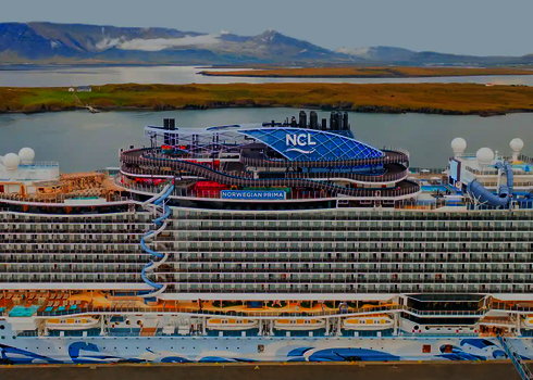 Norwegian Prima Kreuzfahrtschiff mit Wasserpark und Lotus Wasserrutsche im Hafen.