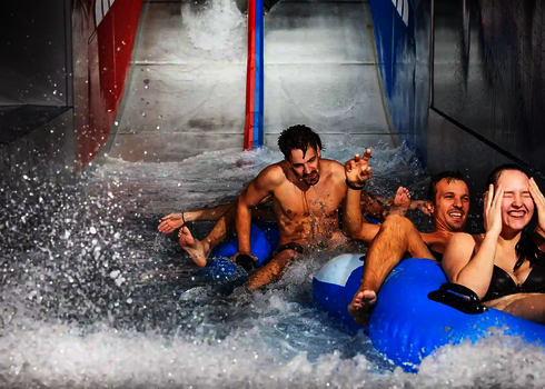Glückliche Badegäste im Wasserbecken nach der Fahrt mit der Raft Racer Reifenrutsche.