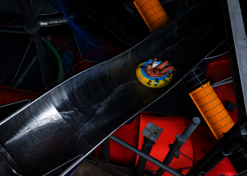 Blick von oben auf eine Person in einem Rutschreifen in einer Crazy River Wasserrutsche aus Edelstahl.