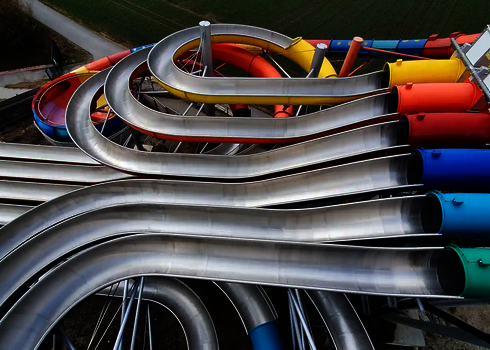  Blick auf die Wasserrutsche Matracer mit mehreren farbigen Röhrenstarts und Edelstahlbahnen.