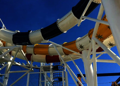 Drei Wasserrutschen, getragen von weißen Stützen, unter freiem, blauen Himmel.