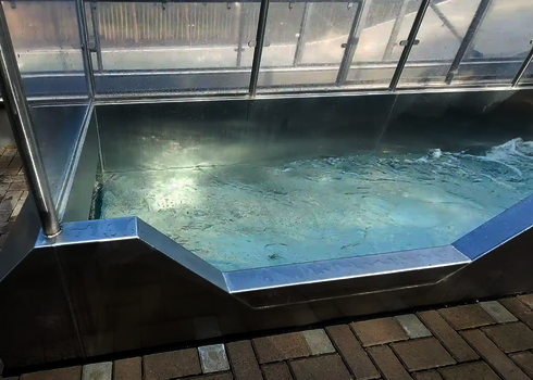 Rectangular stainless steel catch basin with bubbling water and transparent side walls.