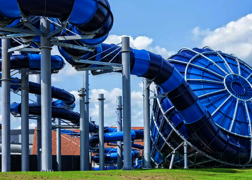 Blauer Cyclone-Trichter mit angrenzender Röhrenrutsche auf Pfeilern bei sonnigem Wetter.