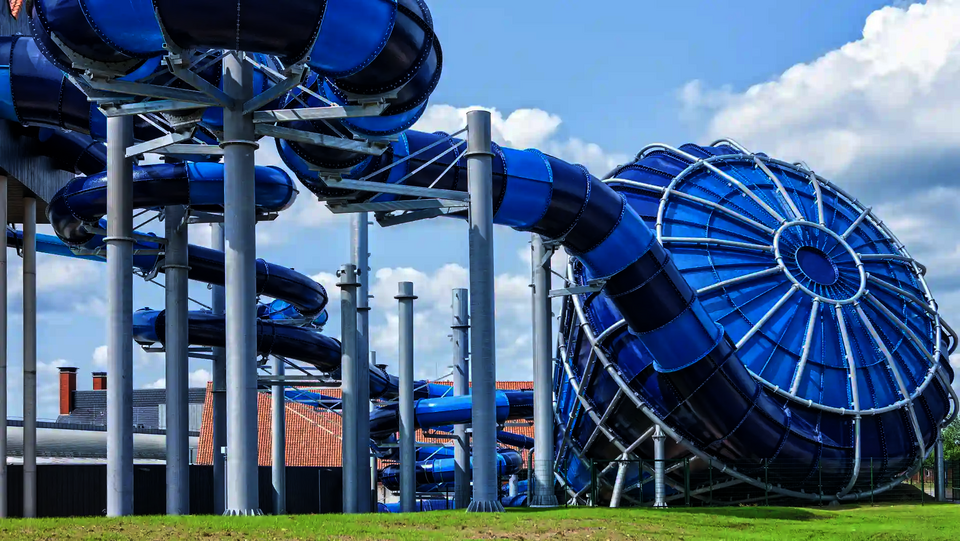 Blauer Cyclone-Trichter mit angrenzender Röhrenrutsche auf Pfeilern bei sonnigem Wetter.