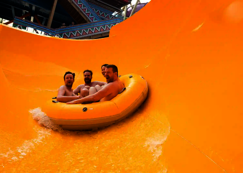 Mehrere Personen rutschen lachend in einem gelben Reifen der Rr2700.