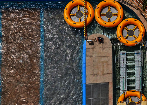 Several yellow slide rafts float in the water basin next to the entrance to the raft conveyor.