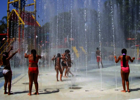 Kinder in Badebekleidung in Wasserpark mit sehr viel spritzendem Wasser.