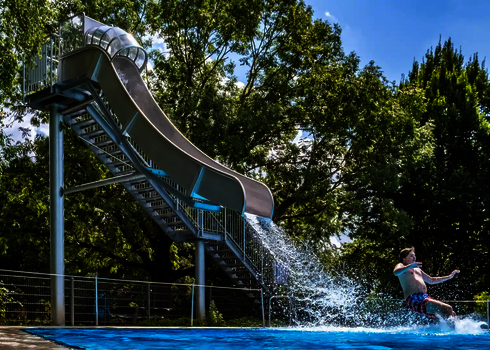 Fallrutsche im Einsatz: Ein Junge landet rutschend im Wasser.