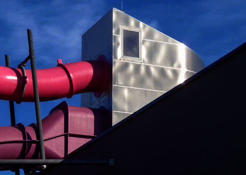 Eine pinke RR1200 Wasserrutsche mit einer Fassadendurchdringung an einem Gebäude.