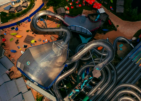Draufsicht auf den Therme Erding Wasserpark mit der Urknall-Wasserrutsche und weiteren Rutschen aus Edelstahl.